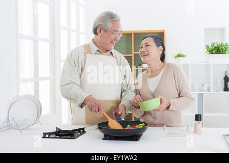 Älteres paar kochen in der Küche und glücklich lächelnd, Stockfoto