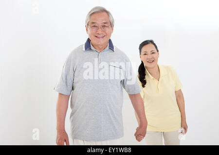 Älteres Paar Hand in Hand und lächelt in die Kamera zusammen, Stockfoto