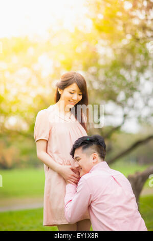 Junger Mann mit schwangere Frau Bauch hören, Stockfoto