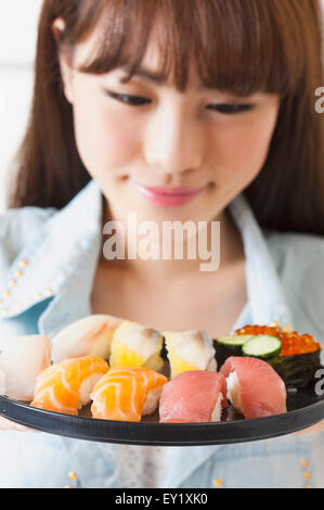 Junge Frau betrachten Sushi mit Lächeln, Stockfoto
