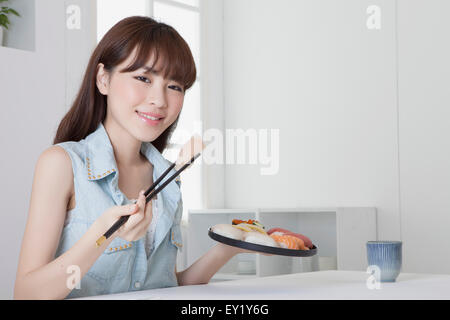 Junge Frau eine Halteplatte japanisches Essen und lächelt in die Kamera, Stockfoto