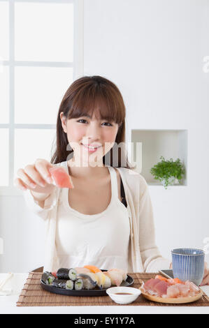 Junge Frau hält Sashimi und lächelt in die Kamera, Stockfoto