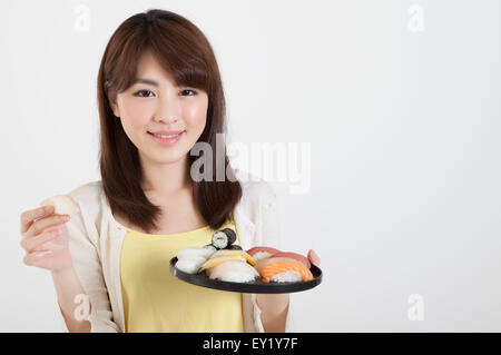 Junge Frau eine Halteplatte japanisches Essen und lächelt in die Kamera, Stockfoto