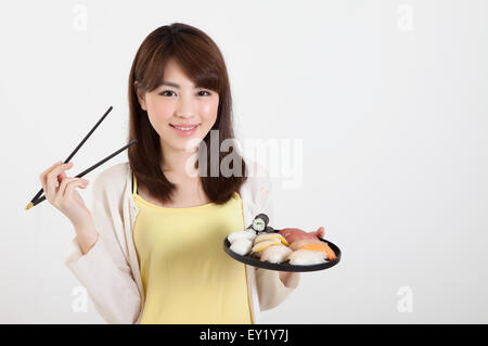 Junge Frau mit Stäbchen und einen Teller mit japanisches Essen, Stockfoto