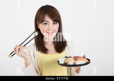 Junge Frau mit Stäbchen und einen Teller mit japanisches Essen mit Lächeln, Stockfoto