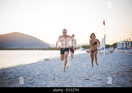 Gruppe junger multiethnischen Freunde laufen im Badeanzug am Strand bei Sonnenuntergang - Freundschaft, Freiheit-Konzept - paar Freunde Stockfoto