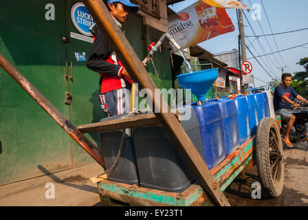Ein Wasserwanderer, der Kanister an einer Wasserstation in Kamal, Jakarta, Indonesien füllt. Stockfoto