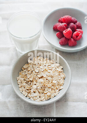 Schüssel Haferflocken mit Himbeeren und eine Tasse Milch Stockfoto