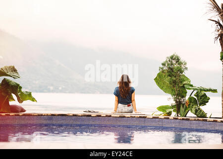 Junge Frau sitzt am Rand des Pool, San Pedro, Lake Atitlan, Guatemala Stockfoto