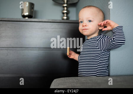 Baby Boy Essen Keks im Wohnzimmer Stockfoto