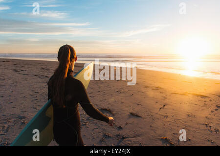 Rückansicht des Surferin zu Fuß am Strand in Richtung Meer, Cardiff-By-The-Sea, Kalifornien, USA Stockfoto