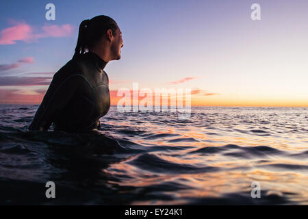 Surferin waten im Meer bei Sonnenuntergang, Cardiff-By-The-Sea, Kalifornien, USA Stockfoto