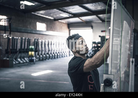 Junger Mann schreiben auf Whiteboards im Fitness-Studio Stockfoto