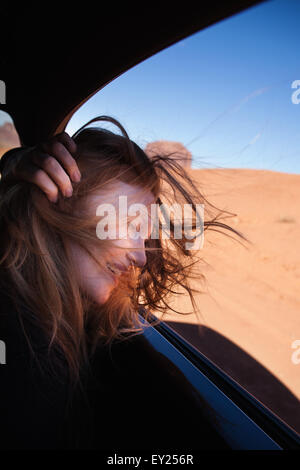 Frau mit windigen Haar am Autofenster, Monument Valley, Utah, USA Stockfoto