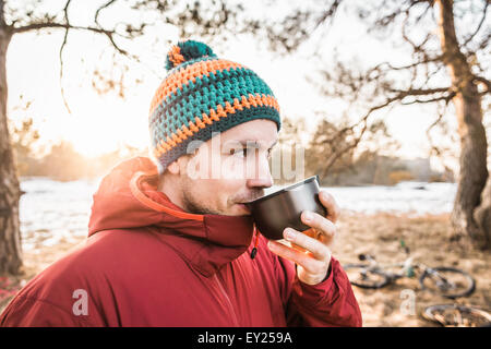 Porträt des jungen männlichen Radfahrer Kaffeetrinken im Wald am See Stockfoto