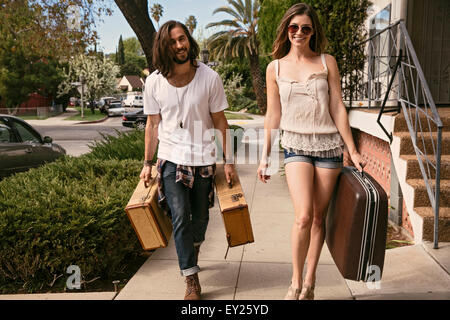 Junges Paar mit Koffern entlang der Straße Stockfoto