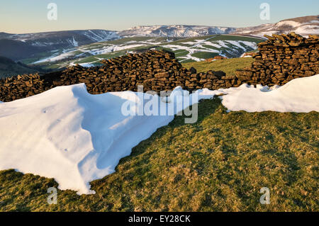 Beautiful Peak District Landschaft im Spätwinter mit Resten von Schneeverwehungen im Abendlicht leuchten. Blick auf Kinder Scout. Stockfoto