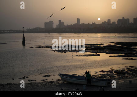 Indische Koli Fischer prüfen ihre Boote am Strand bei Sonnenuntergang in Mumbai, Indien Stockfoto