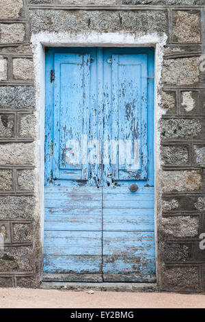 Alte blaue Holztür in grauen ländlichen Steinwand, Hintergrundtextur, Korsika, Frankreich Stockfoto