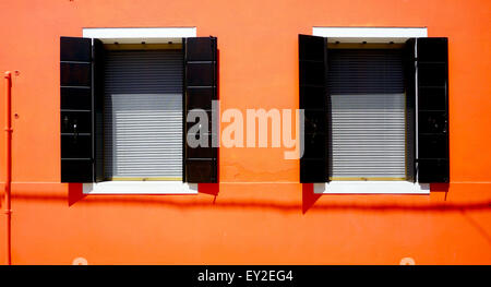 Zwei Windows-Haus in Burano auf orange Wand Gebäudearchitektur, Venedig, Italien Stockfoto