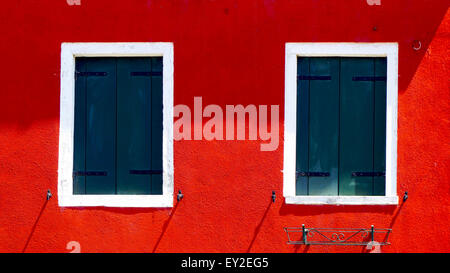 zwei Fenster mit weißen Rahmen auf rote Farbe Wand in Burano Insel, Venedig, Italien Stockfoto