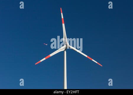 Düsenverkehrsflugzeug durchschaut Rotorblätter von Windkraftanlagen gegen blauen Himmel Stockfoto