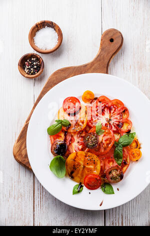 Reife frische bunte Tomaten Salat mit Olivenöl und Balsamico-Essig auf weißem Holz Hintergrund Stockfoto