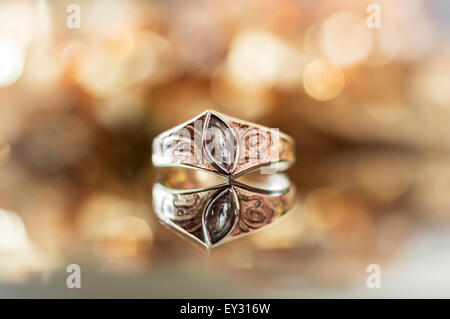 Ein Diamant-Ring mit einer Reflexion, vor einem goldenen gelben leicht verschwommenen Hintergrund Stockfoto