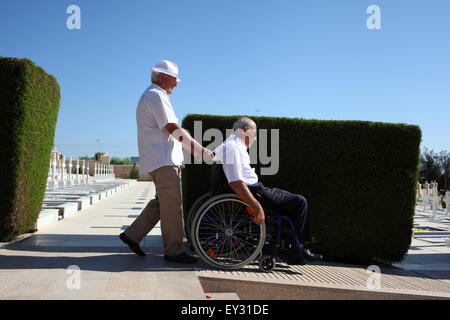 Larnaca, Zypern. 20. Juli 2015. Ein Mann, der im Krieg von 1974 in Zypern verwundet ist verlassen des Friedhofs nach dem Ende der Gedenkstätte, mit der Hilfe eines Freundes. Zypern ist 41 Jahre seit der türkischen Invasion 1974. Bildnachweis: Yiorgos Doukanaris/Pacific Press/Alamy Live-Nachrichten Stockfoto