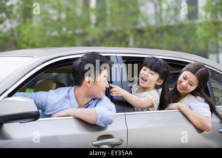 Glückliche junge Familie in einem Auto Stockfoto