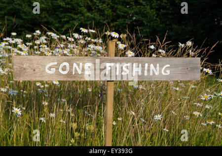 Gone Fishing Zeichen auf einem Pfahl unter Sommerblumen Stockfoto