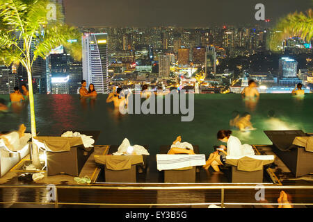 Menschen auf der Suche in der Skyline von Singapur Nacht Blick auf Marina Bay Sands Infinity-Pool Stockfoto