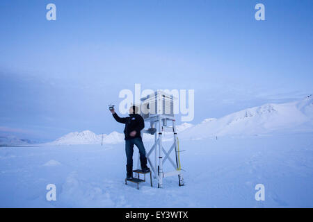 Techniker Jürgen Graeser vom atmosphärischen Observatorium der Forschungsstation AWIPEV untersucht Meteorologische Messtechnik auf einem Bildschirm Stevenson in Ny-Alesund auf Spitzbergen, Norwegen, 9. April 2015. Seit 2003 arbeiten deutsche und französische Forscher in der Forschungsstation AWIPEV in den ehemaligen Bergmann-Siedlungen auf der Inselgruppe Svalbard. Wissenschaftliche Arbeitsgebiete der Koldewey-Station sind die Beobachtung der arktischen Stratosphäre und Untersuchungen des Lebens in und rund um das arktische Meer von Ozeanographen, Ozean Geologen und arktischen Physik. Foto: Jens Büttner Stockfoto