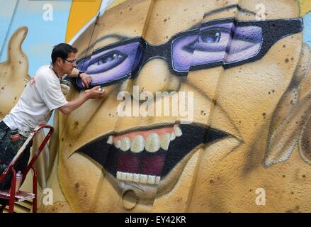 Der Graffitikünstler aus Döbeln, Frank Schäfer aka JFM, arbeitet an seiner Graffiti-Gemälde, das zeigt einen Erdnuss Flip mit Sonnenbrille im Ringelnatz' Heimatstadt Wurzen (Sachsen), Deutschland, 10. Juli 2015. Die zwei von drei Meter-Malerei ist nur einer von vielen gestrichenen Wänden in Vorbereitung des "Tag der Sachsen". Der ausgebildete Fenster Kommode und Graffiti-Künstler Frank Schäfer seinen Lebensunterhalt mit seinem Hobby und entwirft mehrere große Wände in Deutschland im Auftrag von Bau-, Handel- und Autofirmen und Supermärkte. Foto: Waltraud Grubitzsch/ZB Stockfoto