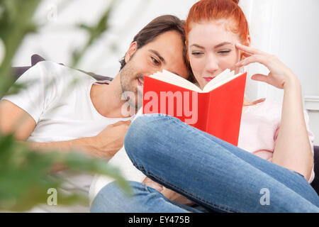 Hautnah süße junge Paar ruht auf dem Sofa in der lebenden Bereich während Lesung ein Buch zusammen ernst. Stockfoto