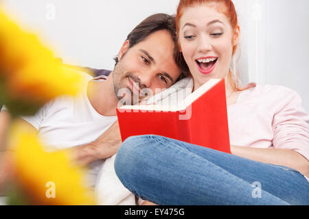 Hautnah süße junge Paar ruht auf dem Sofa in der lebenden Bereich während Lesung ein Buch zusammen ernst. Stockfoto