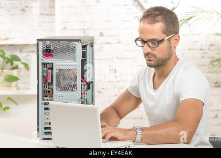 junger Ingenieur repariert einen Computer mit laptop Stockfoto