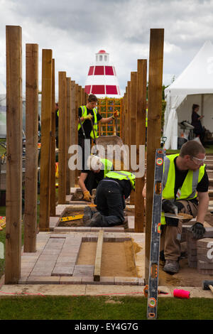 Harte Landschaftsgestaltung in Schaugarten und Landschaft Arbeiter Ausbildung im Tatton Park, Cheshire, UK 23. Juli 2015. Letzte Feinheiten beim 17. Jährlichen RHS Flower Festival Showground als Lehrlinge im Landschaftsbau und Gartenbau ihre Lehrkünste über drei Tage demonstrieren und identische Parzellen in einem unfertigen kleinen Garten mit Spalieren und Pflasterarbeiten produzieren. Stockfoto