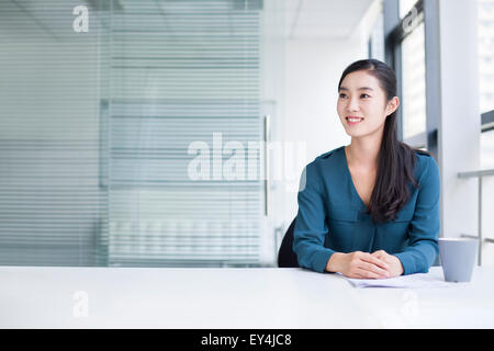 Junge Geschäftsfrau denken im Büro Stockfoto