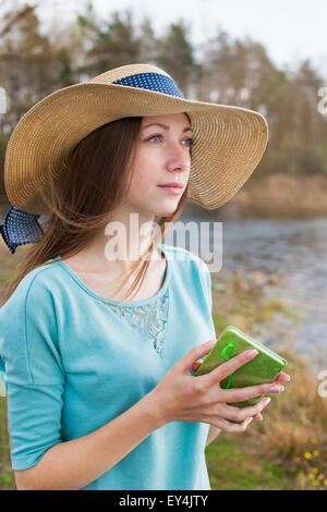 Sommersprossige Mädchen Hut Ruf mit Hinweis auf dem See bei windigem Wetter Stockfoto