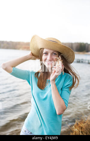 Sommersprossige Mädchen Hut hören Muschel und lächelnd Stockfoto
