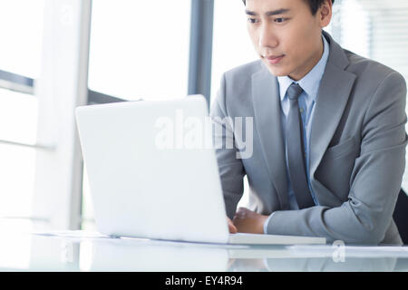 Junger Geschäftsmann mit Laptop im Büro Stockfoto