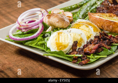 Steak-Spinat-Salat mit Zwiebelringen und Champignons Stockfoto