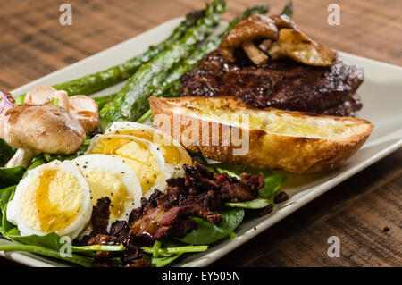 Steak-Spinat-Salat mit Zwiebelringen und Champignons Stockfoto