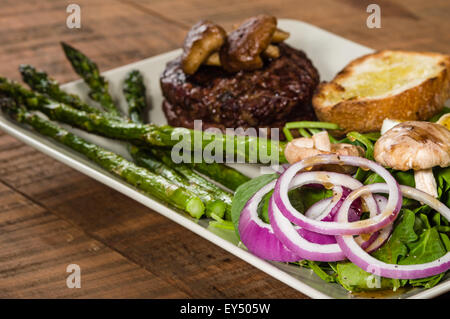 Steak-Spinat-Salat mit Zwiebelringen und Champignons Stockfoto