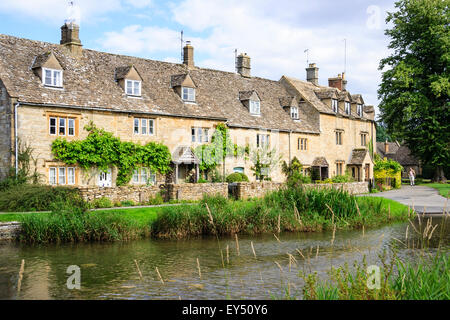 Ansichtskarte Blick auf die Reihe der Cotswold Cottage terrasse Häuser mit den langsam fließenden Fluss Auge im Vordergrund Lower Slaughter. Stockfoto