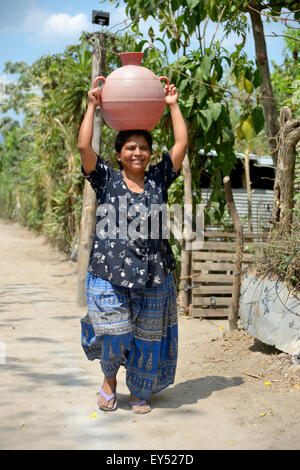 Frau, die Wasser in einen Krug auf dem Kopf, Slum Colonia Monsenor Romero, Distrito Itália, San Salvador, El Salvador Stockfoto