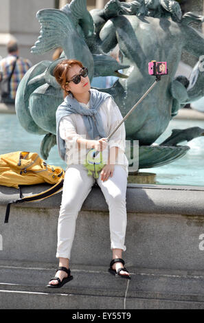 London, England, Vereinigtes Königreich. Japanische Touristen auf dem Trafalgar Square, ein Foto mit einem Selfie-stick Stockfoto