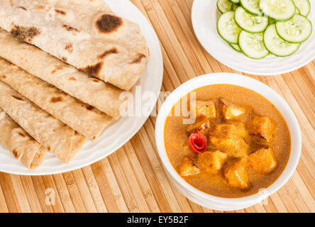 Gefaltete hausgemachte Weizen Chapati (indisches Brot) mit köstlichen indischen Paneer Butter Masala-Gurken-Salat serviert. Stockfoto