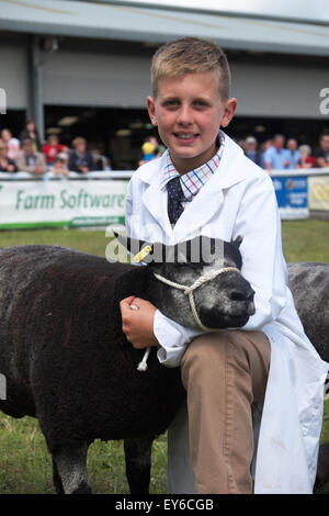 Builth Wells, Powys, Wales, UK. 22. Juli 2015. Tag 3 - Sonne bescheint junge Harry Fuller mit seinem blauen Texel Lamm am Young-Handler-Event auf der Royal Welsh Show teilnehmen. Harry im Alter von entstammt 10 Jahren Whitland, Camarthanshire, Wales.  Die viertägige Veranstaltung zog mehr als 240.000 Besucher und 7.000 Tiere Einträge zu Europas größten Agrarmesse. Stockfoto